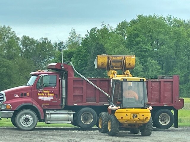 Family Grade & Gravel dump truck being loaded with gravel by JCB skid steer